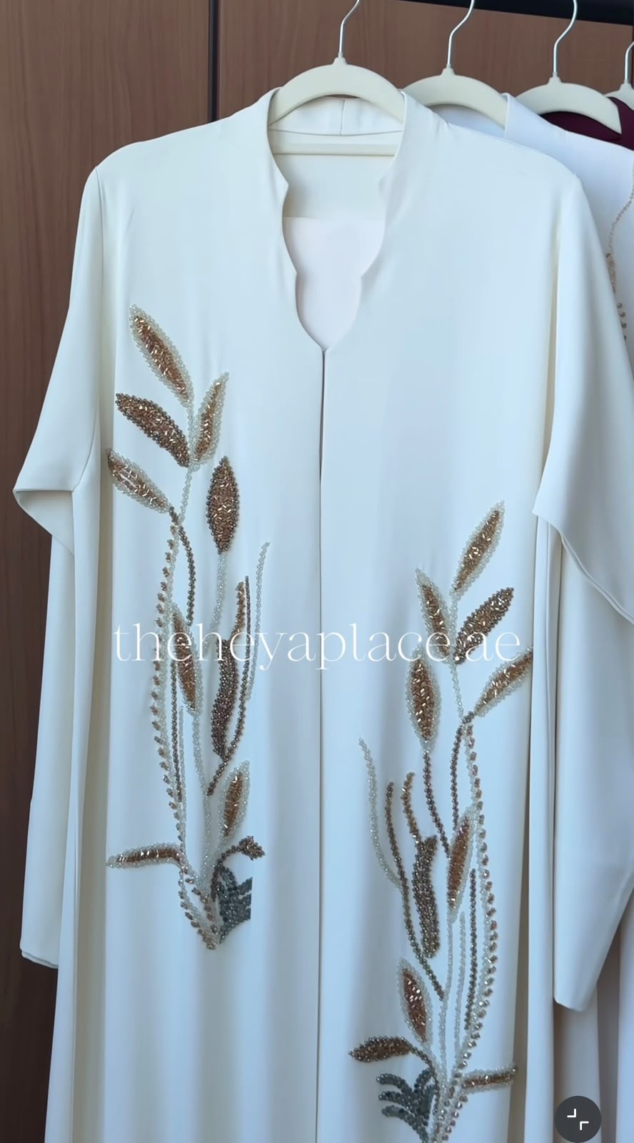 Golden Meadow Abaya in ivory white featuring handcrafted champagne gold botanical embroidery and an elegant flowing silhouette.