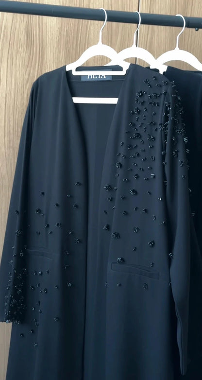 Black Swan Abaya in jet black featuring scattered crystal embellishments, front pockets, and an elegant flowing silhouette.