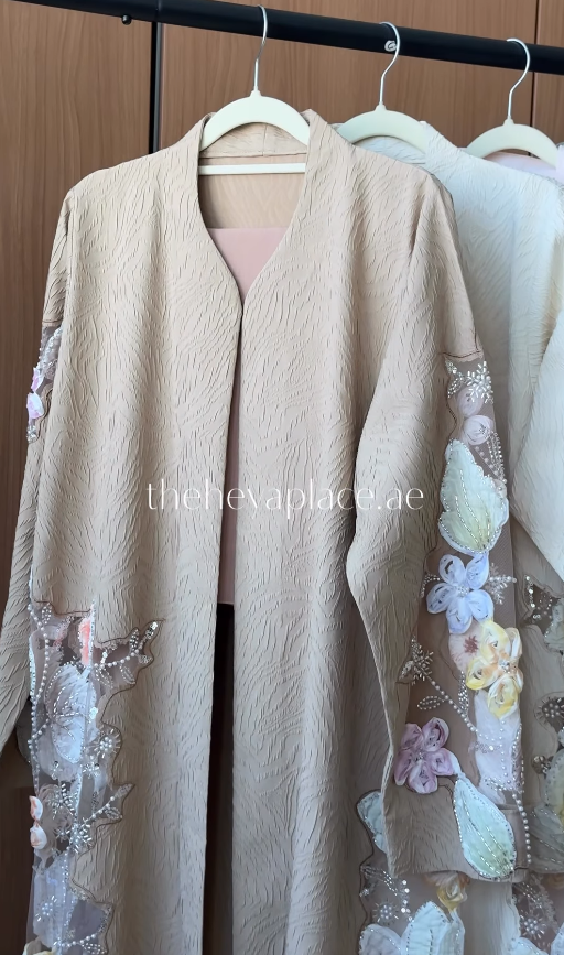 Blossom Veil Abaya in soft beige featuring 3D floral embroidery, pearl embellishments, and sheer embroidered sleeves