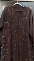 Woman wearing the Chocolate Cascade Abaya in elegant modest design with a flowing silhouette.