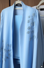 Ocean Bloom Abaya in soft sky blue featuring elegant hand-beaded floral embroidery and a flowing luxury silhouette.