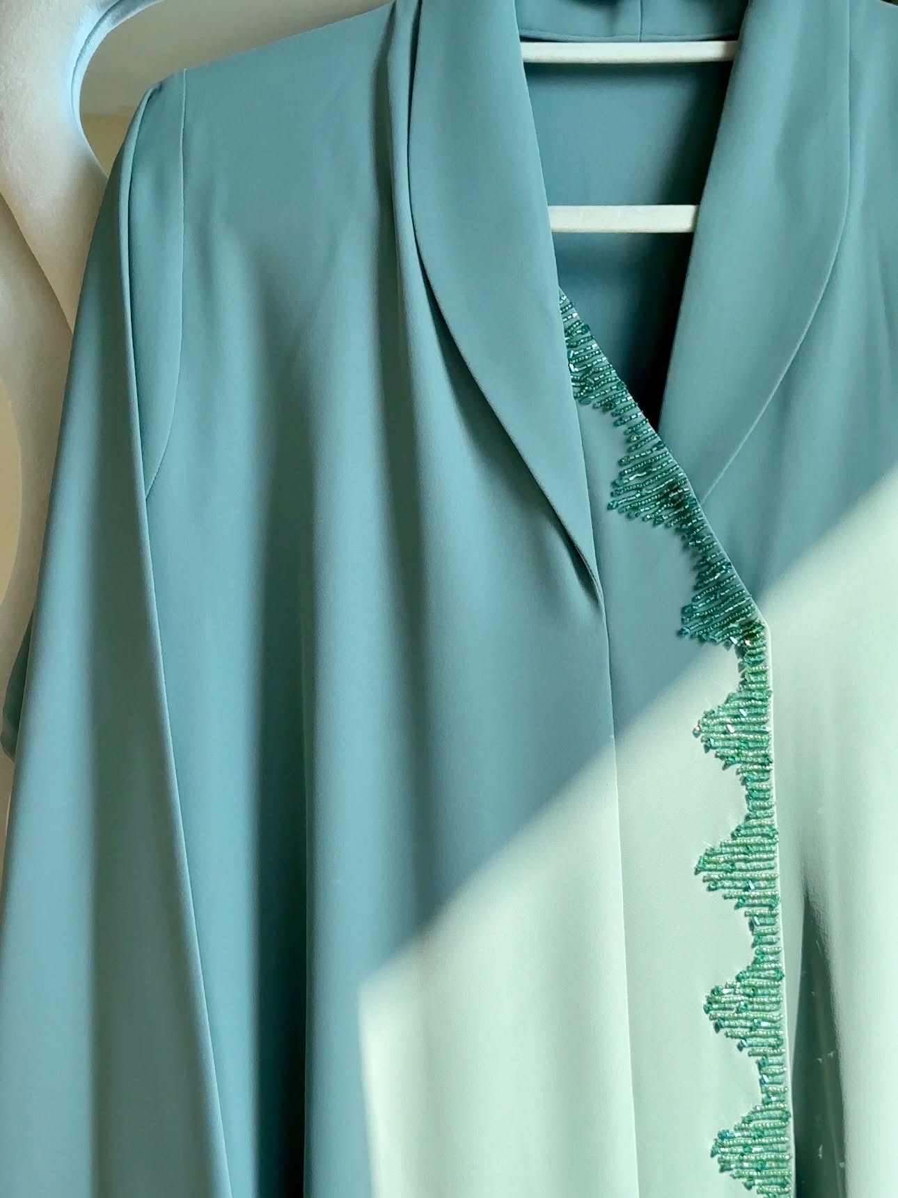 Seafoam Elegance Abaya in soft seafoam green featuring elegant geometric beadwork along the front opening and a graceful flowing silhouette.